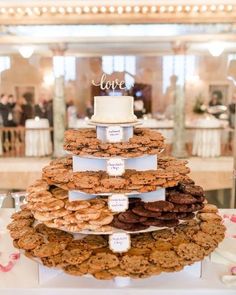 a three tiered wedding cake with cookies on the bottom and love written on top