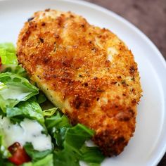 a white plate topped with salad and chicken cut in half on top of lettuce