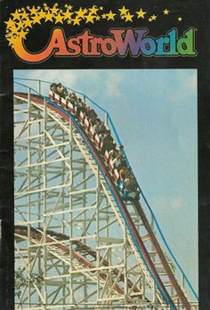 an amusement park with people riding the roller coaster