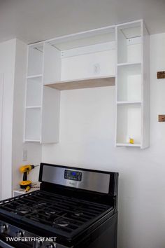 a stove top oven sitting inside of a kitchen next to a wall mounted book shelf