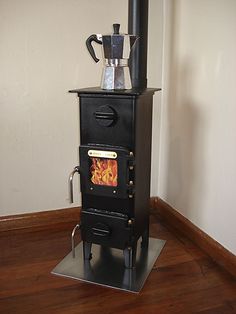 a black stove with a coffee pot on top of it in a room next to a wall