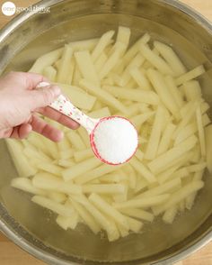 a person spooning sugar over some food in a pot