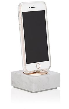 an iphone sitting on top of a white marble block with a gold ring around it