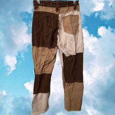 a pair of brown and white pants hanging from a clothes line with clouds in the background