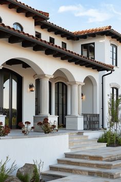 a white house with many windows and steps leading up to the front door that leads to another building