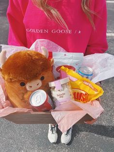 a person holding a teddy bear in a cart full of food and drinks on the street