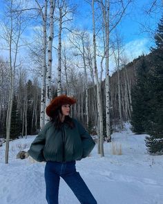 a woman standing in the snow wearing a hat