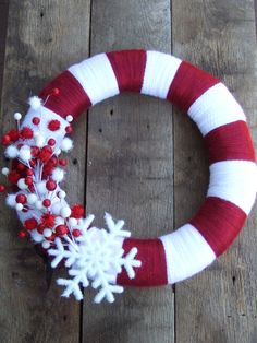 a red and white yarn wreath with snowflakes on it sitting on a wooden surface