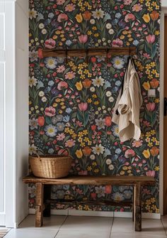 a bench and coat rack in front of a floral wallpapered entryway area