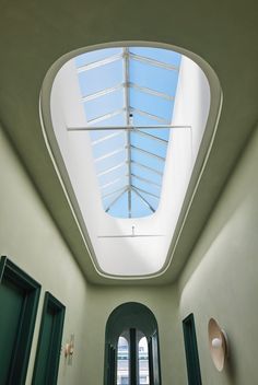 the skylight is shining down into an empty room with green doors and windows on both sides