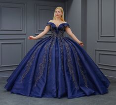 a woman in a blue ball gown posing for the camera with her hands on her hips