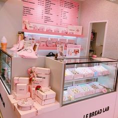 a display case filled with lots of different types of cakes and pastries in front of a pink wall