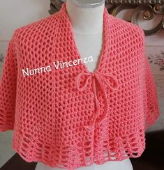 a pink crocheted shawl on top of a mannequin