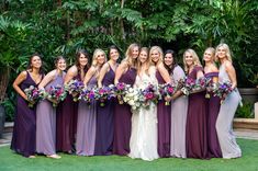 a group of women standing next to each other holding bouquets in front of trees