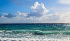 an ocean view with waves crashing on the shore and clouds in the sky above it