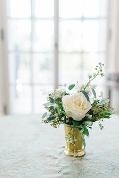 a vase filled with white flowers sitting on top of a table next to a window