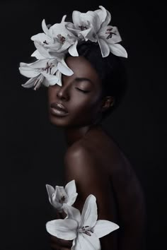 a woman with white flowers on her head and black skin, in front of a dark background