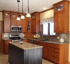 a large kitchen with wooden cabinets and granite counter tops, along with stainless steel appliances