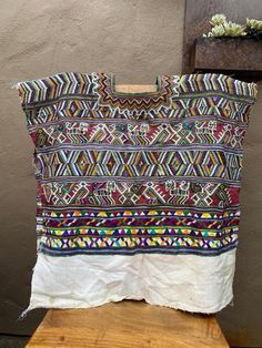 a multicolored bag sitting on top of a wooden table next to a potted plant