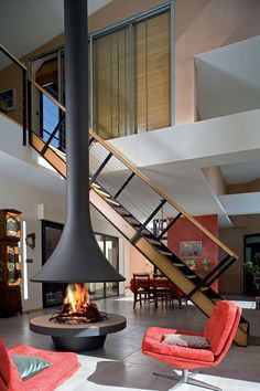 a living room with red chairs and a fire place in the middle of the room