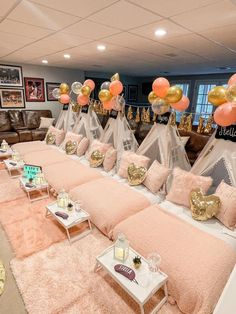 a room filled with lots of pink and gold balloons in the shape of teepees