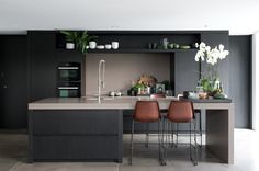 a kitchen with two brown chairs sitting at the center of the counter and an island in front of it