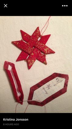 some red and gold ornaments are on a white tablecloth with string attached to them