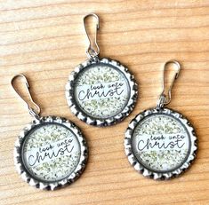 three bottle cap earrings with words on them