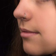 a woman with nose piercings on her nose looking to the side, close up