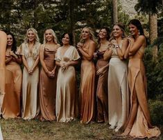 a group of women standing next to each other in front of some trees and grass