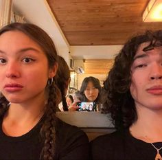 two young women with braids standing next to each other in front of a mirror