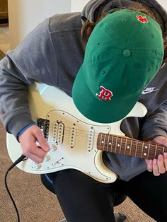 a person with a hat on and playing an electric guitar in front of them,