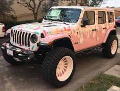 a pink jeep parked in front of a building with graffiti on it's side