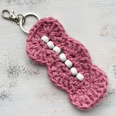 a pink crocheted key chain with white buttons