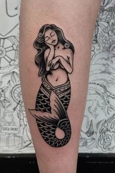 a black and white photo of a mermaid tattoo on the right leg, with an image of a woman hugging her baby