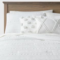 a bed with white sheets and pillows on top of it