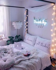 a bed with white sheets and lights around it