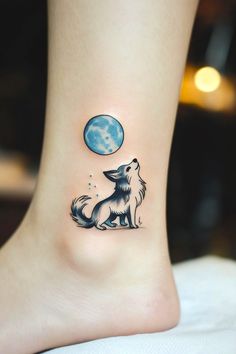 a small tattoo on the ankle of a woman with a wolf and moon behind it