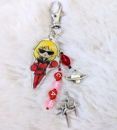 a keychain with an anime character and charms attached to it on a white fur surface