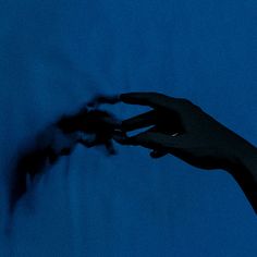 a person's hand reaching for something in the air at night, against a blue background