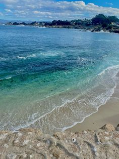 the beach is clear and blue with waves coming in from the water's edge