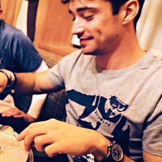 two men sitting at a table with food in their hands and one man holding a fork