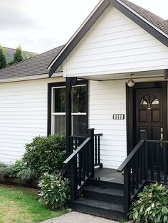 a small white house with black steps leading up to the front door