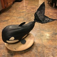 a sculpture of a black whale on top of a wooden board in a kitchen with tile flooring