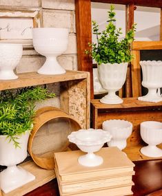 several white vases and bowls on display in a room with wooden boxes, mirrors and other items