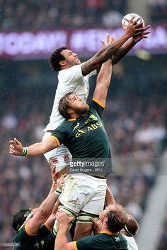 the rugby players are trying to catch the ball in mid air as they jump for it