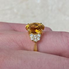 a woman's hand holding an orange and white diamond ring