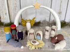 small crocheted nativity figurines are displayed on a wooden surface in front of a white arch