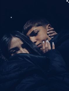 two people are hugging in the dark with their hands on each other's shoulders