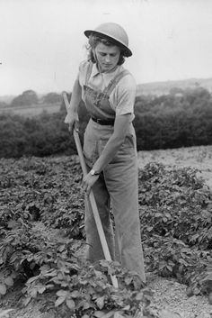 an old black and white photo of a woman working in a field with a shovel